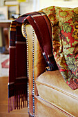 Woolen blanket and embroidered textile hang on the arm of a leather armchair