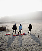 Kinder, die mit Schlitten über ein Feld in Dorset laufen