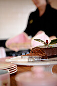 Frau mit Backblech und Schokoladenkuchen auf einem Kuchenständer