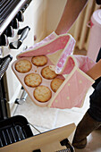 Woman putting a tray of mince pies in range oven