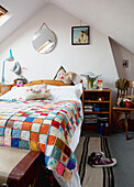 Patchwork crotchet blanket on double bed in attic bedroom