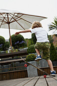 Young boy playing on a skateboard in the back garden