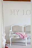 Detail of upholstered chaise in a bedroom with My Love in bold lettering on the wall