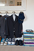 Boys school uniform hanging beneath a mirror with shoes and books