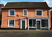 Sunlit painted house exterior and shop front 
