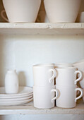 Weiße Tassen und Teller in einem Küchenregal