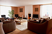 Brown sofas with coffee table and lit fire in painted white chimney breast