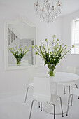 Blumenvase auf einem Spiegel in einem ganz in Weiß gehaltenen Esszimmer