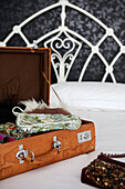 Beaded handbags in open suitcase on white cast iron bed
