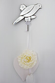 Mirrored bird ornament and rose hanging on wall