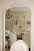Dining room with crystal drop chandelier reflected in mirror with painted frame