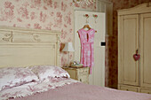 Pink dress hangs on back of door in pink floral papered room