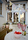 Party bunting and wineglasses in whitewashed backyard