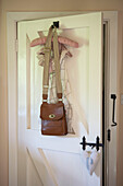 Satchel and fabric clothes hangers hang on back of bedroom door with latch