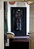 Gemustertes Kleid hängt an der schwarzen Tür im Schlafzimmer eines georgianischen Bauernhauses
