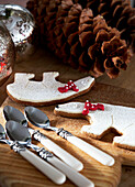 Teelöffel und Tannenzapfen mit Weihnachtsplätzchen auf dem Tisch