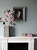 Cut flowers with artwork on painted Georgian townhouse mantlepiece