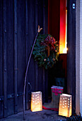 Lit lanterns and Christmas wreath at doorway of 16th Century Welsh farmhouse