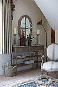 Painted side table with matching candlesticks and oval shaped mirror in entrance hall 