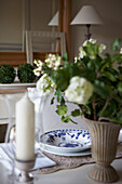 Patterned plate and candle with cut flowers on dining table