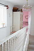 Glass fronted wardrobe and chandelier in hallway landing with open door to pink bedroom