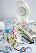 Cut flowers books and clock on Devon cottage bedside table