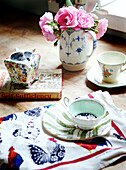 Cut flowers and chinaware with tea towel and book on self-sufficiency
