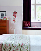 Dressmakers dummy and quilted bedspread in bedroom with window seat