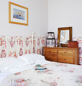 Hot water bottle on bed with patterned panelling and wooden chest of drawers
