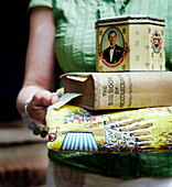 Woman holding cushion with tin and book of needlecraft
