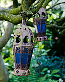 Two Moroccan lanterns hang in trees
