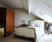 Antikes Bett und hölzerner Kleiderschrank im ausgebauten Dachgeschoss