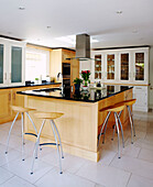 Wooden bar stools at kitchen island with black shiny worktop