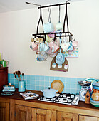 Ceiling mounted crockery rack above hob unit set in wooden kitchen counter