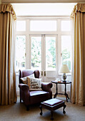 Leather armchair and footstool in bay window