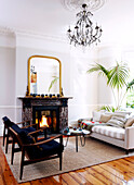 Lit fire in living room with matching armchairs and glass chandelier