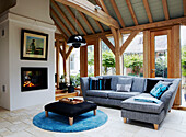 Beamed conservatory with grey sofa and contrasting black and turquoise detail