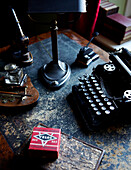 Typewriter on distressed leather desktop with inkwell and other vintage objects