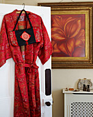 Bright red silk dressing gown hanging on the back of a panel door