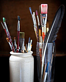 Artists paint brushes in a stone jar and glass