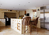 Checked splashback and kitchen island with rattan high stools in cottage