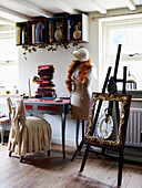 Desk and easel with mannequin at window of country cottage