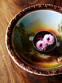Cut flowers floating in painted ceramic bowl