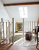Antique birdcage on landing of spiral staircase in country cottage