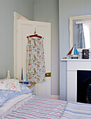 Summer dress hangs on back of door in fresh blue bedroom