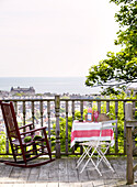 Schaukelstuhl mit Tisch auf einem Balkon im Freien mit Blick auf das Meer