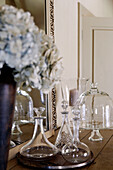 Glassware and cut flowers on sideboard in country home