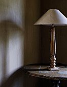 Cream lamp with carved base on side table in country home