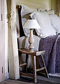 Purple quilted bed covers and bedside lamp in country home