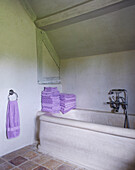 Folded lilac towels on bath surround in country home